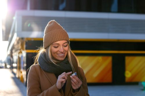 young adult woman applying lip balm on a winter day